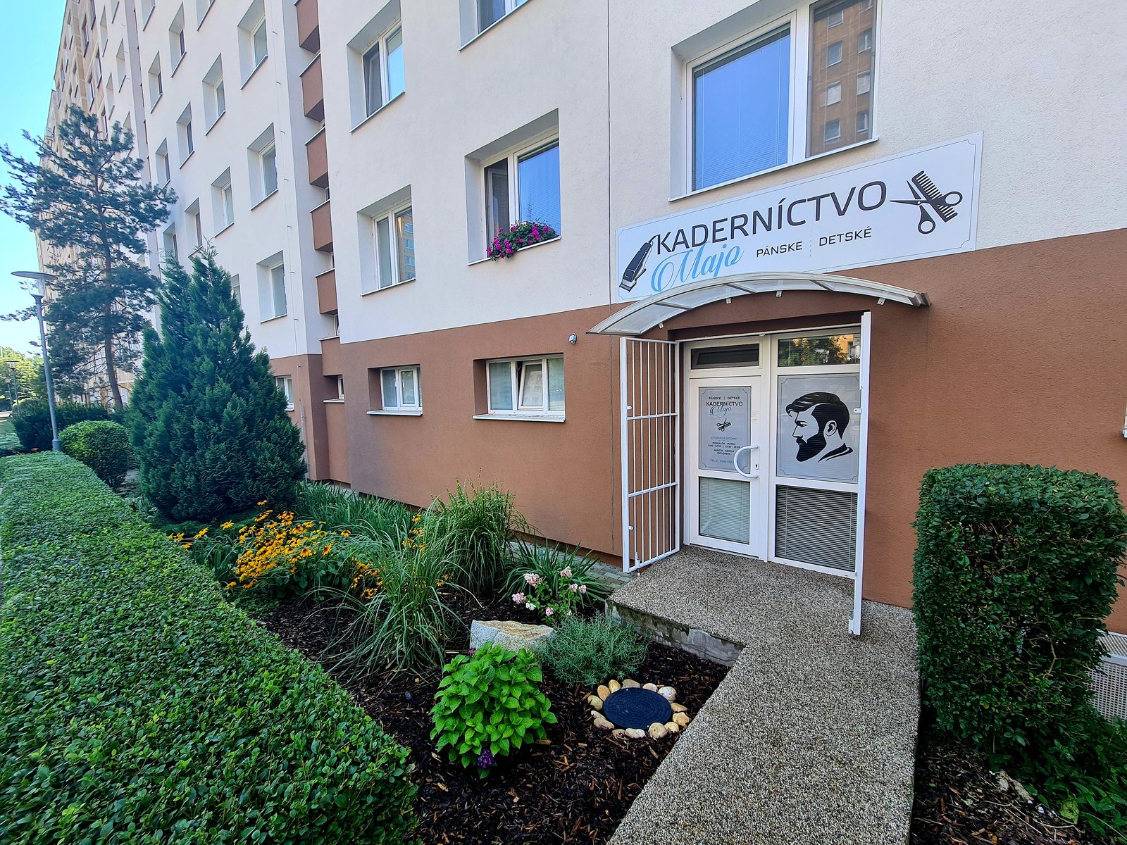 Panelový dom na Eisnerovej 15 so vchodom do Kaderníctva Majo a predzáhradkou